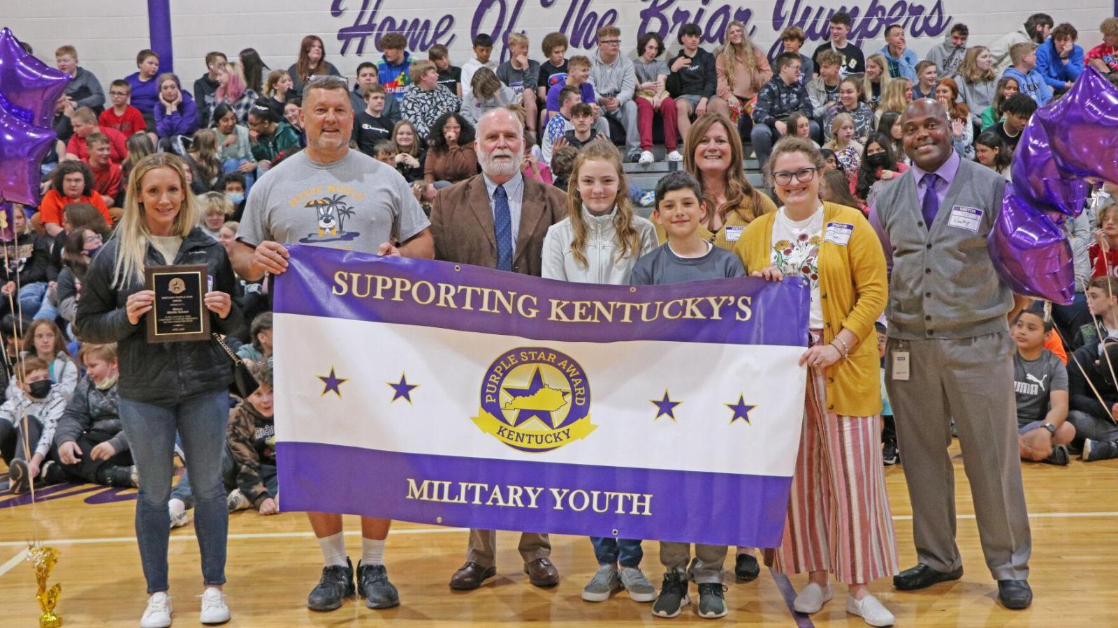 Students and staff at Meece Middle School hold their Purple Star Award sign during a ceremony.