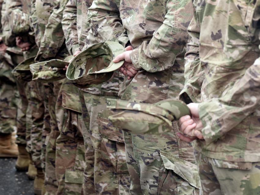 a photograph of soldiers in fatigues standing with hats in hands