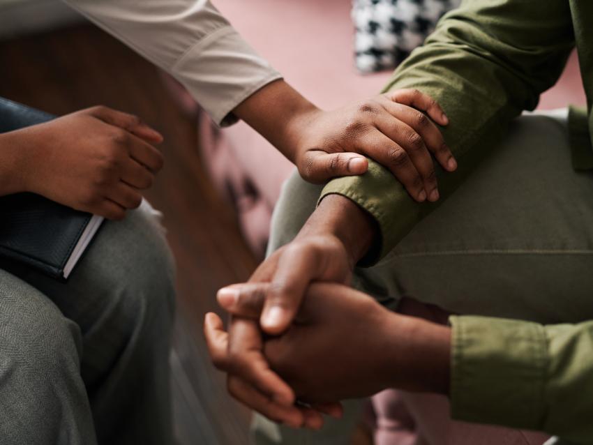 a pair of hands grasp each other while another hand holds the wrist