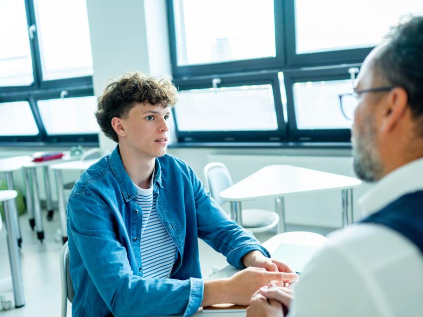 Teacher supporting struggling student with learning difficulties during lesson.