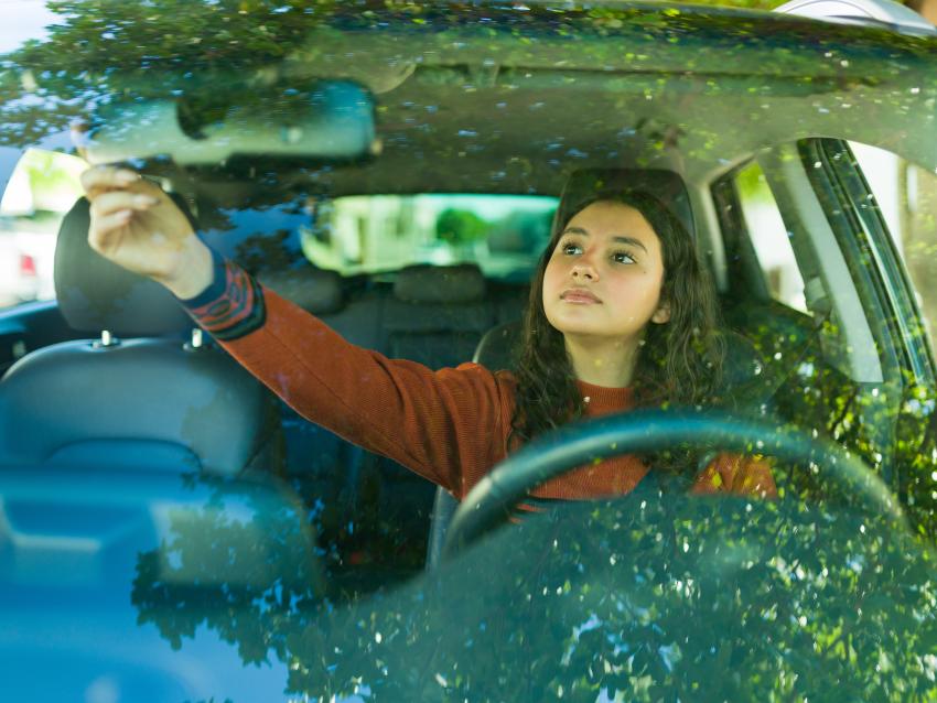 teen driver adjusting car mirror