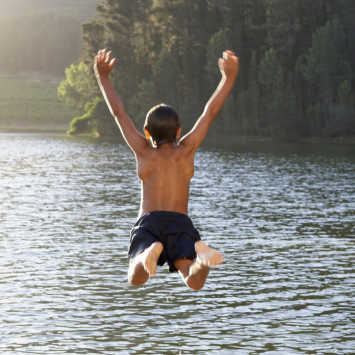 Boy jumping in lake 