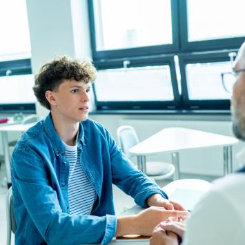 Teacher supporting struggling student with learning difficulties during lesson.