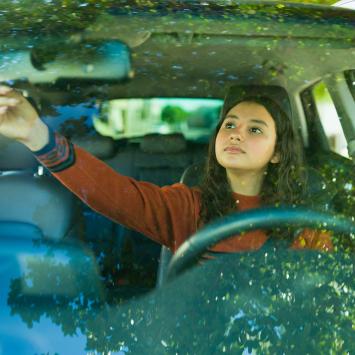 teen driver adjusting car mirror